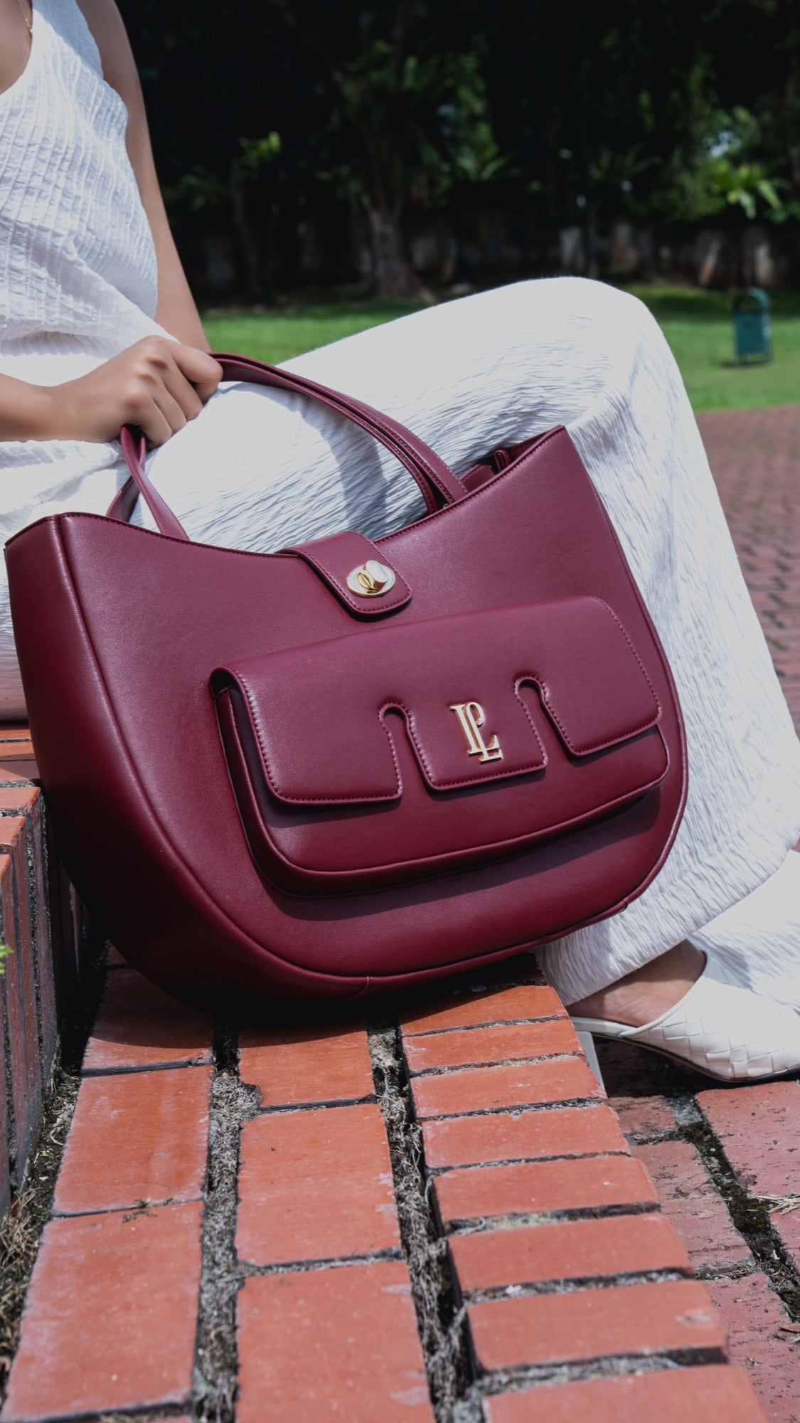 The Levain bag in Merlot burgundy on a wooden bench, beside an open magazine